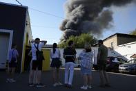 People watch as smoke rises from a pyrotechnics warehouse in Moscow, Russia, Saturday, June 19, 2021. A large fire broke out at a fireworks depot in the center of Moscow. The fire is raging at the area of 500 square meters, Russia emergency services said in the statement. (AP Photo/Pavel Golovkin)