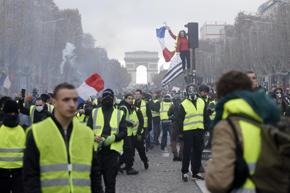 FILE - In this Nov. 24, 2018, file photo, demonstrators march on the famed Champs-Elysees avenue in Paris, France, as they protest the rising of the fuel prices. “Yellow vest” protests have gripped France for four weeks, blocking highways from Provence to Normandy and erupting in rioting in Paris. They’ve shaken the country to its core and left President Emmanuel Macron struggling to retain control. (AP Photo/Kamil Zihnioglu, File)