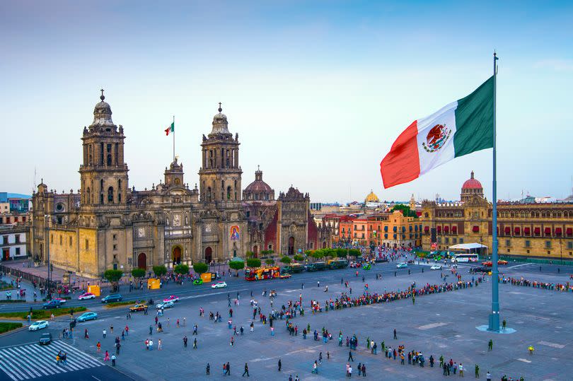 The Mexican flag flies over the Zocalo, the main square in Mexico City.  The Metropolitan Cathedral faces the square, also referred to as Constitution Square.