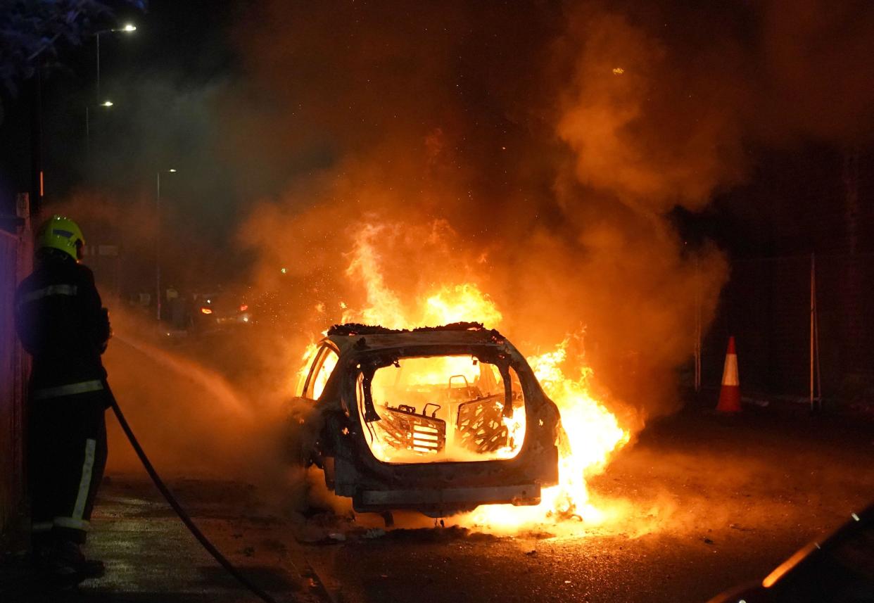 Firefighters tend to a burning police car burns as officers are deployed on the streets of Hartlepool following a violent protest. Videos on social media show a crowd of people in a street, with one showing a youth throwing objects at a line of police in riot gear holding shields. It comes after similar disorder in Merseyside and Whitehall, London after the mass stabbing in Southport that claimed the lives of three girls and left eight more children and two adults injured. Picture date: Wednesday July 31, 2024.