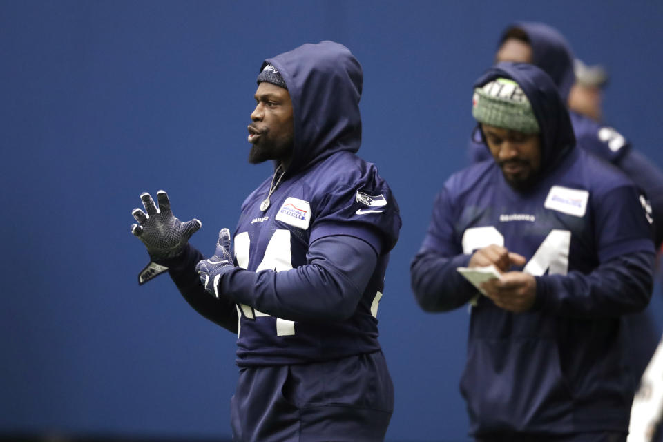 Seattle Seahawks running back Robert Turbin, left, stands near running back Marshawn Lynch, who looks over notes during warmups at the NFL football team's practice facility Tuesday, Dec. 24, 2019, in Renton, Wash. (AP Photo/Elaine Thompson)