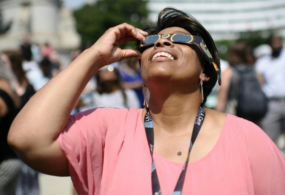 To view a solar eclipse directly, experts say protective glasses, such as the ones this woman in Washington, D.C., is wearing in 2017, are a must.