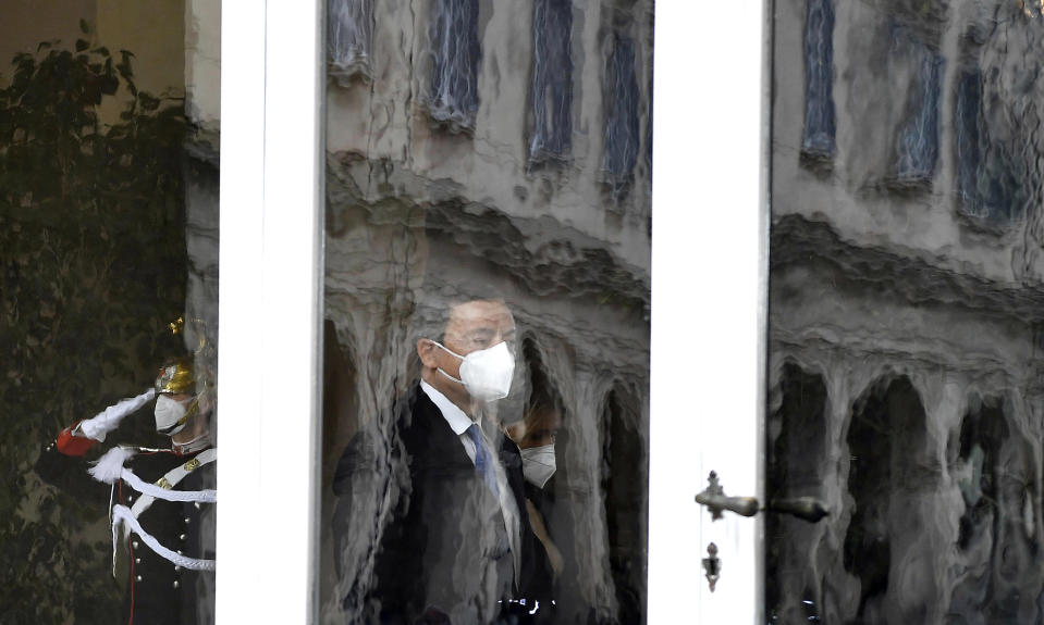 Former European Central Bank President Mario Draghi, center, framed by a window, passes by a Cuirassier Regiment's guard as he arrives at the Quirinale presidential palace for talks with Italian President Sergio Mattarella to discuss a mandate to form a new government, in Rome, Wednesday, Feb. 3, 2021. (Ettore Ferrari/Pool via AP)