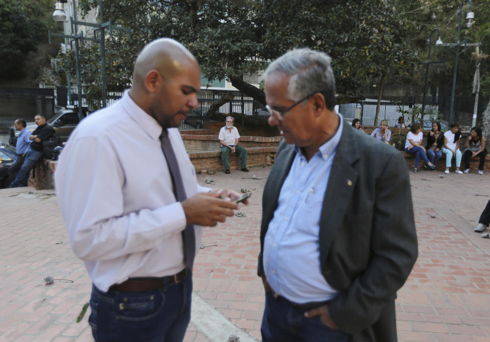 In this Feb. 19. 2019 photo, Danny Golindano, left, a volunteer doctor, speaks with his collage Juan Requesens, father jailed lawmaker Juan Requesens, prior a meeting for recruiting volunteers, at a square in Caracas, Venezuela. The citizen brigade is one of the most ambitious undertakings Venezuela’s opposition has attempted. (AP Photo/Fernando Llano)