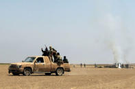 Fighters of the Syrian Islamist rebel group Jabhat Fateh al-Sham cheer on a pick up truck near the wreckage of a Russian helicopter that had been shot down in the north of Syria's rebel-held Idlib province, Syria August 1, 2016. REUTERS/Ammar Abdullah/File Photo