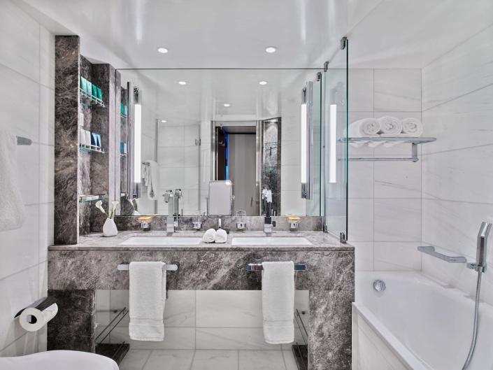 a white and marble modern bathroom with a sink and tub