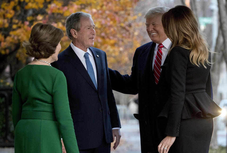 President Donald Trump and first lady Melania Trump are greeted by former President George Bush and former first lady Laura Bush outside the Blair House across the street from the White House in Washington, Tuesday, Dec. 4, 2018. (AP Photo/Andrew Harnik)