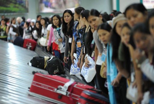 Philippine workers, who had been working in Syria, wait for their luggage after they disembarked from a plane chartered by the International Organization for Migration at the international airport in Manila. Over 260 Philippine workers returned from Syria, recounting tales of the violence that forced them to flee the country, even if it meant risking poverty at home