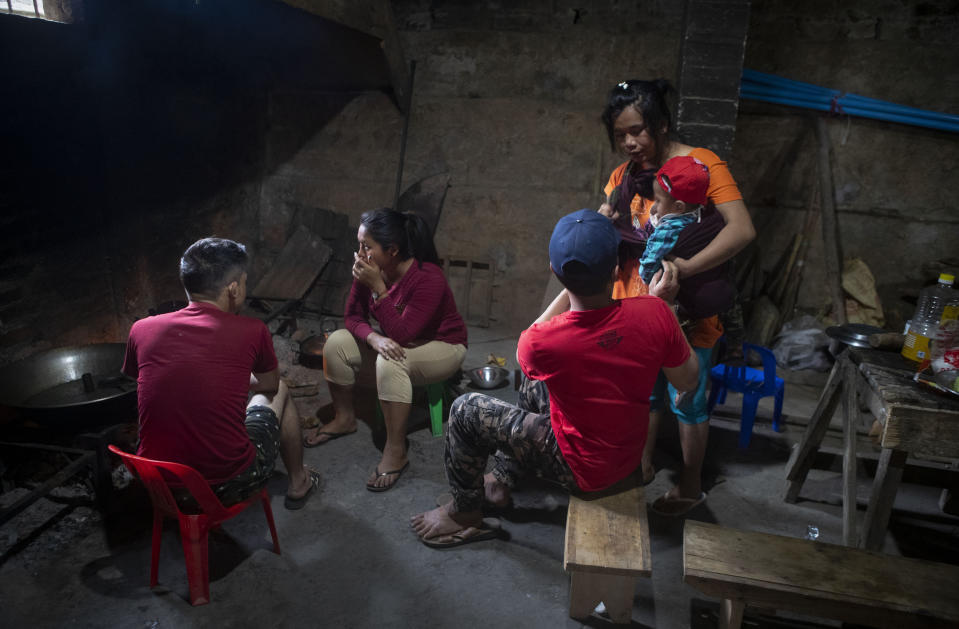 Wife of police officer who fled Myanmar following a military coup hands over her infant to her husband as they prepare food at an undisclosed place in Mizoram, a state bordering Myanmar, India, Friday, March 19, 2021. Several Myanmar police officers who fled to India after defying army orders to shoot opponents of last month’s coup in their country are urging Prime Minister Narendra Modi’s government to not repatriate them and provide them political asylum on humanitarian grounds. (AP Photo/Anupam Nath)