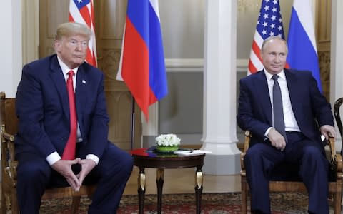 Donald Trump sits upright while Vladimir Putin leans back in his chair - Credit: Mikhail Metzel/TASS