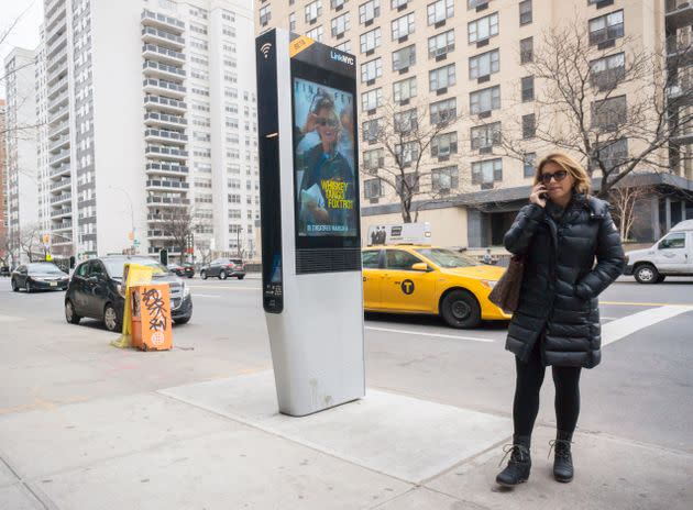 A woman stands near a LinkNYC kiosk in New York City. These kiosks provide free Wi-Fi, phone charging and phone calls. The system is supported by advertising running on the sides of the kiosks. (Photo: Richard Levine via Getty Images)