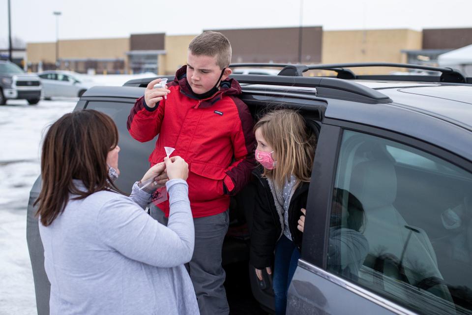 Shani Hessenthaler, of Ann Arbor, helps her son Emmett, 9, and daughter Stella, 7, with a saliva test at the LynxDx drive-thru COVID-19 test site in Ypsilanti on Jan. 6, 2022.