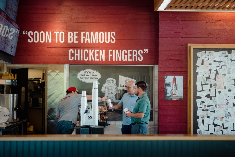 Two customers in a fast food restaurant with red brick walls are served their food.