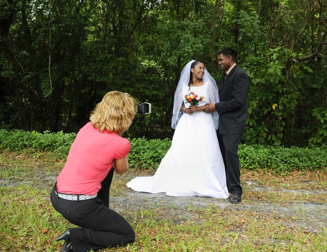 A woman taking a photo of the bride and groom.