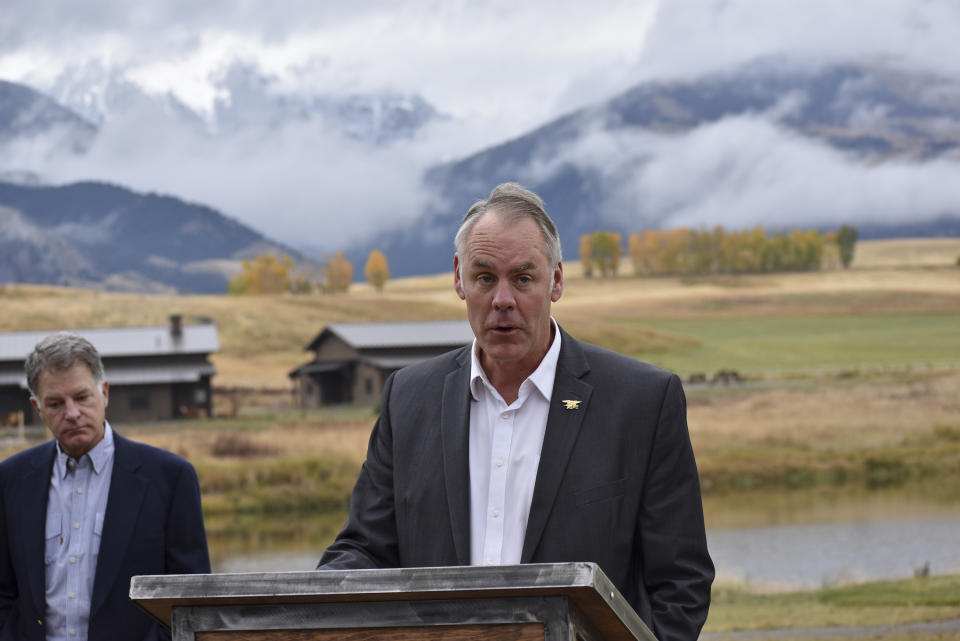 In this Oct. 8, 2018 photo, U.S. Interior Secretary Ryan Zinke announces a ban on mining claims north of Yellowstone National Park as K.C. Walsh, left, president of Simms Fishing Products, listens near Emigrant, Mont. The Trump administration is considering using West Coast military bases or other federal properties as transit points for shipments of U.S. coal and natural gas to Asia as officials seek to bolster the domestic energy industry and circumvent environmental opposition to fossil fuel exports, according to Zinke and two Republican lawmakers. (AP Photo/Matthew Brown)