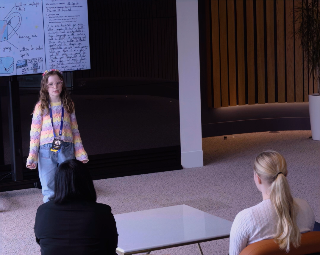 Schoolgirl delivers a speech in front of two adults