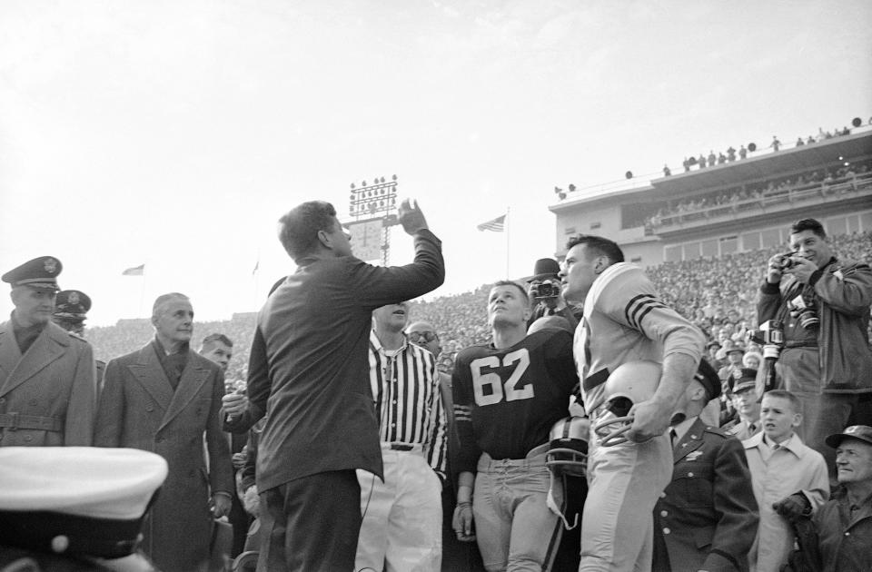 President John F. Kennedy flipped the coin on the field as Navy Captain John Hewitt, right, and Army Captain Michael Casp (62) watched the flip before the start of the 62nd meeting between the Army and the Navy in Philadelphia, Dec. 2, 1961. The game is being played at Philadelphia Stadium. President Kennedy was the first chief executive to see an Army-Navy game in nine years.