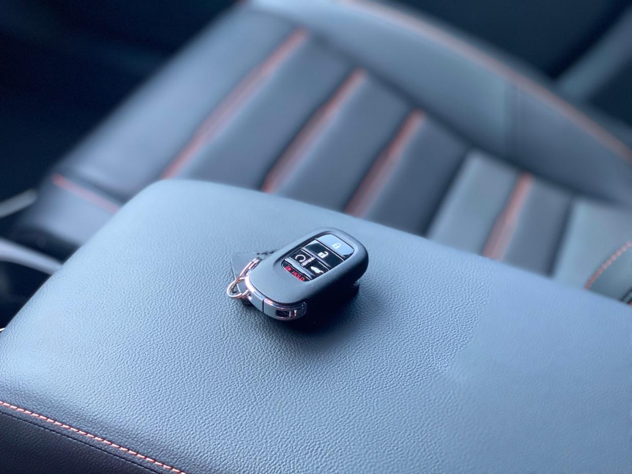 The key fob of a 2025 Honda CR-V Hybrid SUV on the center console arm rest.