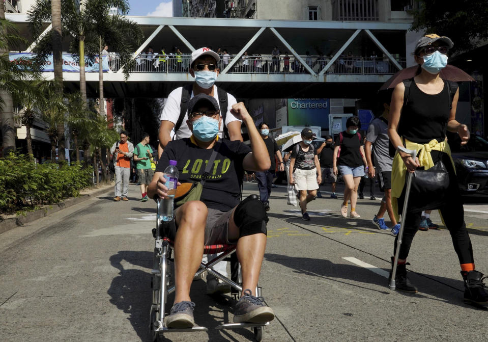 A masked protester in a wheelchair joins a march in Hong Kong on Saturday, Oct. 5, 2019. All subway and trains services are closed in Hong Kong after another night of rampaging violence that a new ban on face masks failed to quell. (AP Photo/Vincent Yu)