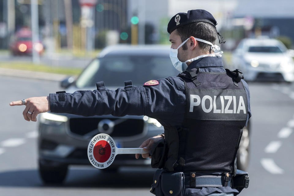 A Police officer stops and check vehicles in Rome, Saturday, April 11, 2020. Using helicopters, drones and stepped-up police checks to make sure Italians don't slip out of their homes for the Easter holiday weekend, Italian authorities are doubling down on their crackdown against violators of the nationwide lockdown decree. The new coronavirus causes mild or moderate symptoms for most people, but for some, especially older adults and people with existing health problems, it can cause more severe illness or death. (Roberto Monaldo/LaPresse via AP)