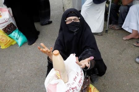 A woman sits next to food supplies she received from a local charity in Sanaa, Yemen, June 23, 2016. REUTERS/Mohamed al-Sayaghi/Files