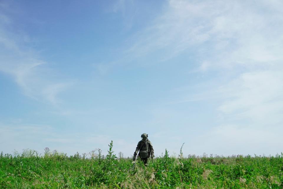 This photograph taken on June 23, 2023, shows a Russian serviceman wearing Explosive Ordnance Disposal (EOD) equipment demining a field at the Novoazovsk district in the Donetsk region.