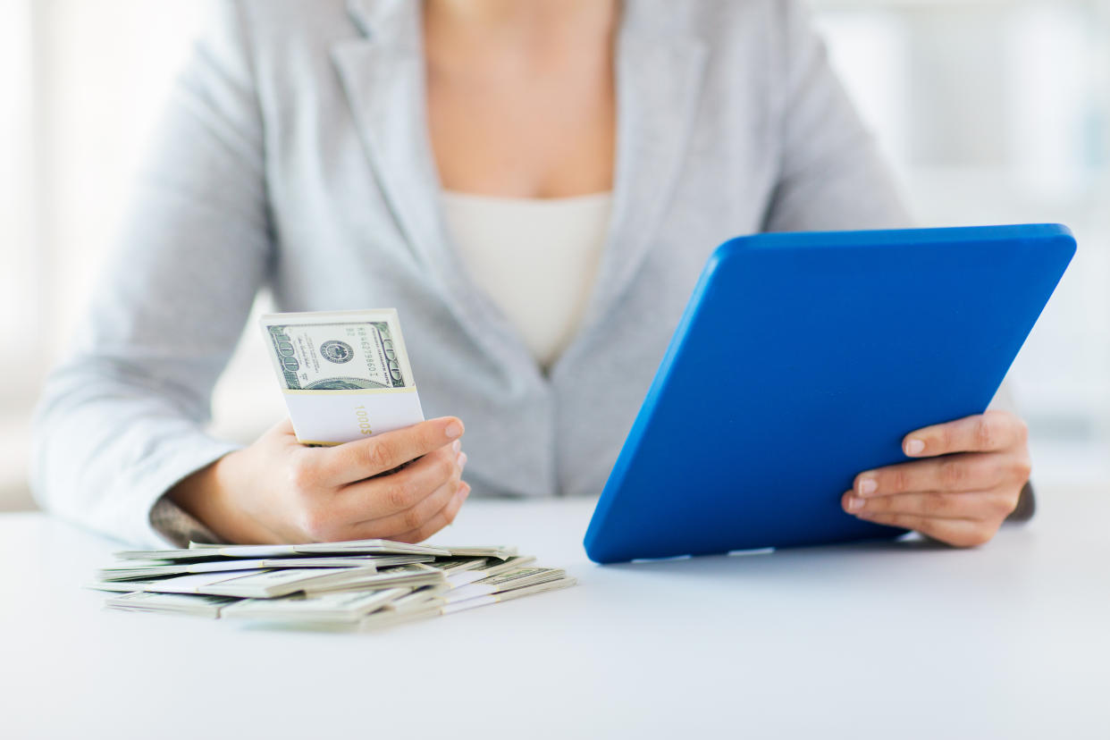 close up of woman hands with tablet pc and money