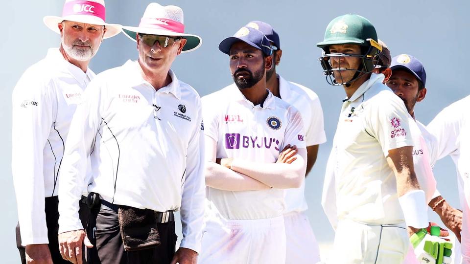 Umpires Paul Reiffel and Paul Wilson, Mohammed Siraj and Tim Paine, pictured here look at the crowd during a suspension in play at the SCG.