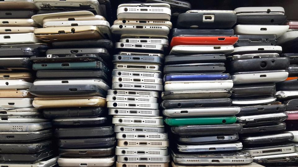 Tall rows of stacked trade-in smartphones of various brands and colors. 