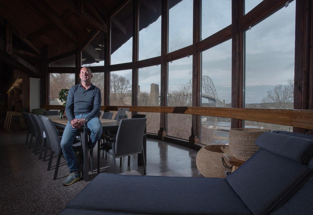 Outdoor furniture is displayed March 15 at the new Tulp Outdoor Living store at the base of the Sagamore Bridge in Bourne, with company principal Gabriel Kroeze. The bridge is in the background. The location was once a Christmas Tree Shops store, known for its thatched roof and windmill.