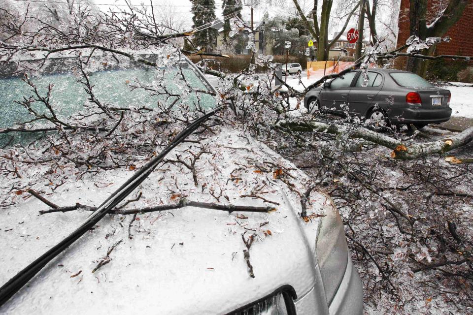 A downed powerline runs over a parked vehicle after ice covered tree branches came down after freezing rain in Toronto, Ontario