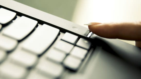 Woman using a fingerprint sensor on a laptop.