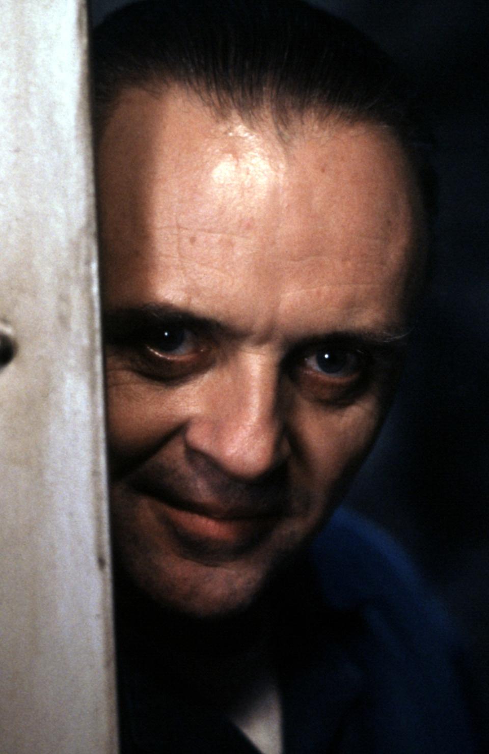 Close-up of Anthony Hopkins as Dr. Hannibal Lecter peeking from behind a wall in 