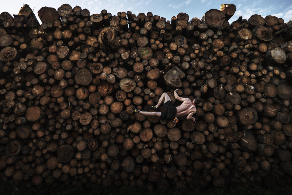 In this image released by World Press Photo, Thursday April 15, 2021, by Adam Pretty, Getty Images, titled Log Pile Bouldering, which won first prize in the Sports Singles category, shows Georg climbs a log pile while training for bouldering, in Kochel am See, Bavaria, Germany, on Sept. 15, 2020. (Adam Pretty, Getty Images, World Press Photo via AP)