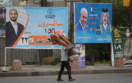 A man walks past campaign banners of candidates ahead of parliamentary election, in Baghdad, Iraq April 22, 2018. REUTERS/Khalid al Mousily