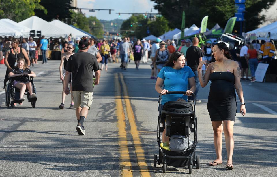 Sisters Kayla Gonzalez, pushing a stroller with her infant son, Jy'air Eaddy, and Mariah Esquilin, all of Erie, walk north on State Street toward Perry Square at CelebrateErie in downtown Erie in 2022.