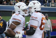 Texas running back Roschon Johnson (2) and offensive lineman Jake Majors (65) celebrate after a touchdown during the second half of an NCAA college football game against West Virginia in Morgantown, W.Va., Saturday, Nov. 20, 2021. (AP Photo/Kathleen Batten)