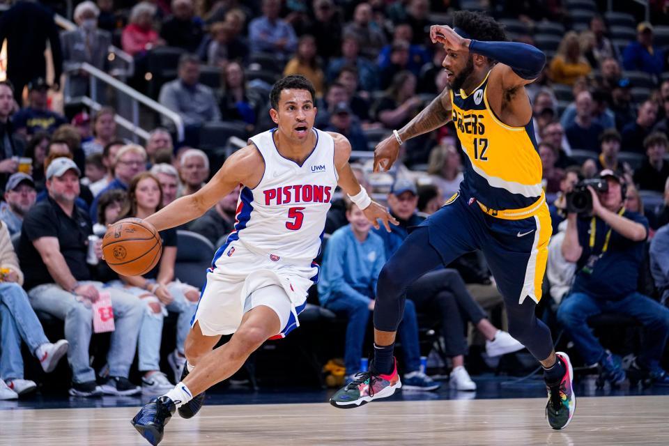 Detroit Pistons guard Frank Jackson (5) drives under Indiana Pacers forward Oshae Brissett (12) during the first half of an NBA basketball game in Indianapolis, Sunday, April 3, 2022. (AP Photo/Michael Conroy)