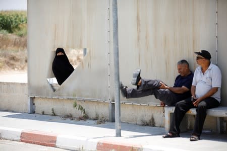 Palestinians rest on a bench at the Israeli side of Erez crossing, on the border with Gaza
