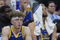 Golden State Warriors guards Brandin Podziemski, left, and Stephen Curry sit on the bench during the second half of the team's NBA basketball play-in tournament game against the Sacramento Kings, Tuesday, April 16, 2024, in Sacramento, Calif. (AP Photo/Godofredo A. Vásquez)
