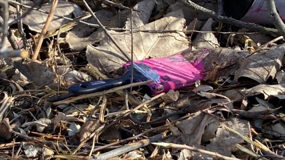 A paintbrush coated with pink paint remained on the ground below the vandalized billboard on Tuesday morning.