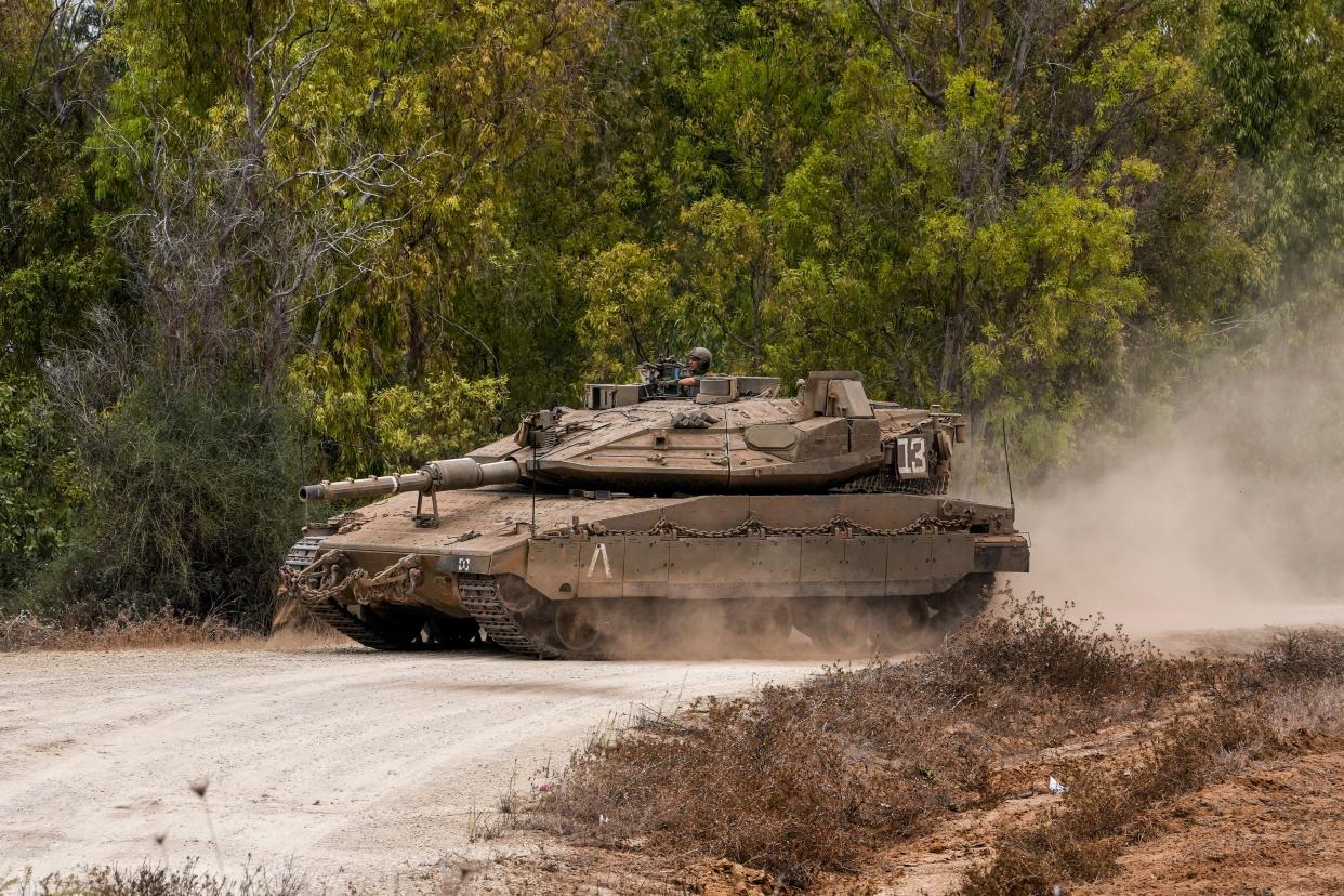 An Israeli tank crosses a road as it advances towards a staging ground near the Israeli Gaza border, southern Israel, Monday (AP)