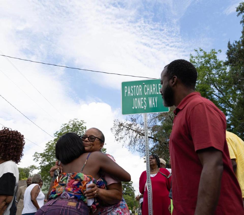 Royce Forman (far left) hugs Valencia Davis Jones, wife of Charles Jones, near the newly unveiled Pastor Charles Jones Way on Friday, June 28, 2024, on Plant Street in Macon, Georgia. Jones, who passed away earlier this month, served as the pastor of Greater Rising Star Full Gospel Tabernacle Church for almost 30 years and as a city councilman for 12 years.