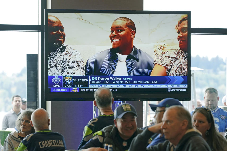 Seattle Seahawks fans watch as Georgia pass rusher Travon Walker is shown on a TV monitor as he is picked by the Jacksonville Jaguars as the top pick in the NFL football draft, Thursday, April 28, 2022, at a Seahawks draft day party in Renton, Wash., near Seattle. (AP Photo/Ted S. Warren)