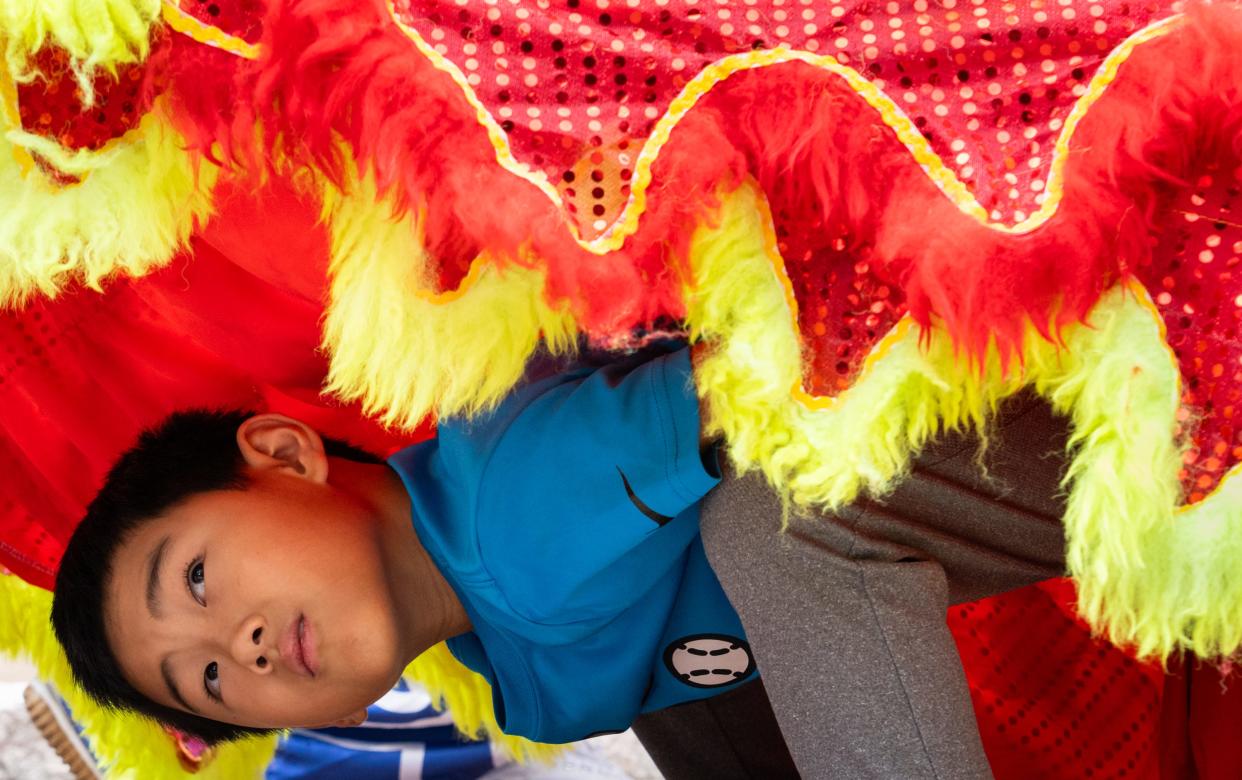 Even Qui peers out from underneath the lion costume while learning and practicing lion dancing with Heavenly Dragon Lion Dance Association at the Fo Guang Shan Xiang Yun Temple in Austin, May 11, 2024. Lion dance involves two dancers- one controlling the head and front feet and the other controlling the back feet.