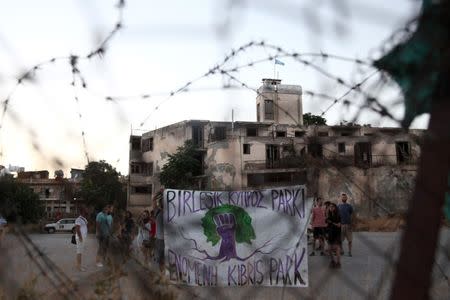 Greek Cypriots and Turkish Cypriots hold a banner inside the UN-controlled buffer zone in Nicosia, Cyprus June 28, 2017. The banner reads in Greek and Turkish, "United Cyprus Park". REUTERS/Yiannis Kourtoglou