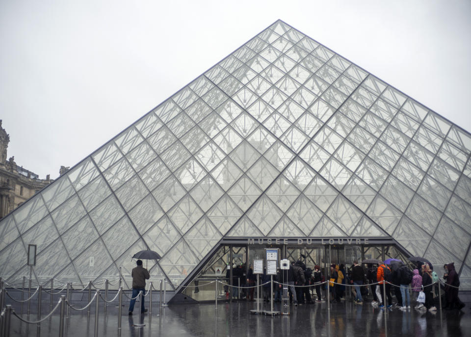 Tourists stand outside the Louvre museum, in Paris, France, Sunday, March 1, 2020. The spreading coronavirus epidemic shut down France's Louvre Museum on Sunday, with workers who guard its trove of artworks fearful of being contaminated by the museum's flow of visitors from around the world. (AP Photo/Rafael Yaghobzadeh)