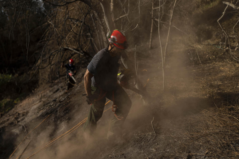 Firefighters clear debris in Kula, Hawaii, Tuesday, Aug. 15, 2023, following wildfires that devastated parts of the Hawaiian island of Maui. (AP Photo/Jae C. Hong)