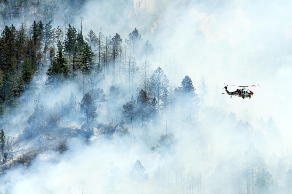 A helicopter flies above smoke as the Toll Fire burns near Calistoga, Calif., on Tuesday, July 2, 2024. An extended heatwave blanketing Northern California has resulted in red flag fire warnings and power shutoffs. (AP Photo/Noah Berger)