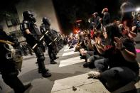 Protesters sit in the street facing a line of riot policemen during nationwide unrest following the death in Minneapolis police custody of George Floyd, in Raleigh